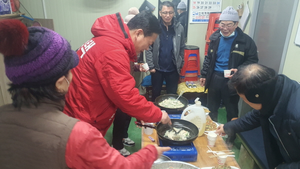김정택 예비후보(빨간점프)가 지역주민들에게 음식을 만들어 주고 있다.